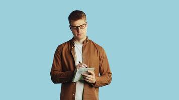 Redhead man taking notes on blue background video