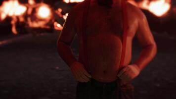 Clown putting on suspenders in front of fire video