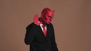Red devil businessman listening and pointing on brown background video