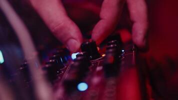 Sound engineer carefully rotating the knob of the mixing controller by the hand close up during the show under concert lights and stage smoke video