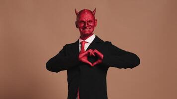 Red devil businessman making heart symbol with hands video