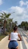 A young woman is biking along a beautiful and scenic coastal path lined with palm trees video