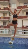 A dynamic balance pose being performed over a pool while skillfully handling a soccer ball video