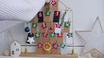 Number on craft paper notes with tasks before Christmas holidays. Female making kraft paper for handmade advent calendar Made with your own hands step by step DIY crafts do it yourself video