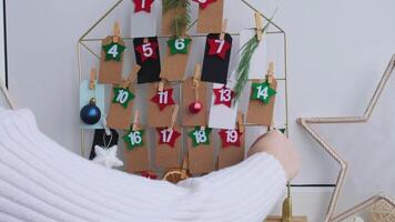 Number on craft paper notes with tasks before Christmas holidays. Female making kraft paper for handmade advent calendar Made with your own hands step by step DIY crafts do it yourself video