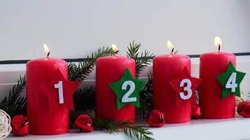 New year and Christmas preparation. Four red advent candles with numbers burning in white windowsill. Handmade eco-friendly decor. Sustainable Christmas decoration atmospheric video