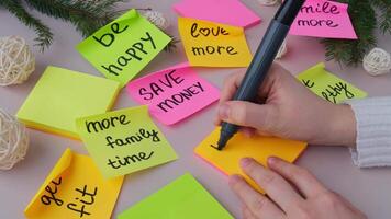Female hands writing handwritten new year resolutions aims goals on sticky notes. Preparation for New Year. Concept of planning and setting goals for personal development video
