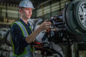 male engineer workers maintenance automatic robotic arm machine in a factory. worker checking and repairing automatic robot hand machine. photo
