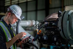 male engineer workers maintenance automatic robotic arm machine in a factory. worker checking and repairing automatic robot hand machine. photo