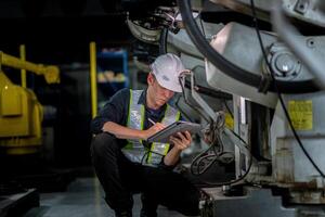 male engineer workers maintenance automatic robotic arm machine in a factory. worker checking and repairing automatic robot hand machine. photo