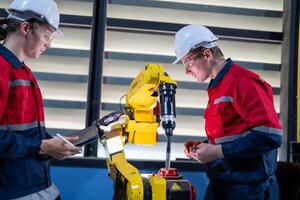 male engineer workers maintenance automatic robotic arm machine in a factory. worker checking and repairing automatic robot hand machine. photo