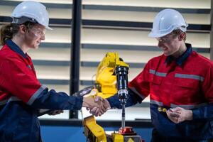 male engineer workers maintenance automatic robotic arm machine in a factory. worker checking and repairing automatic robot hand machine. photo
