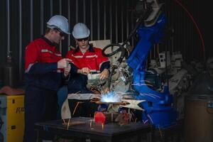 male engineer workers maintenance automatic robotic arm machine in a factory. worker checking and repairing automatic robot hand machine. photo