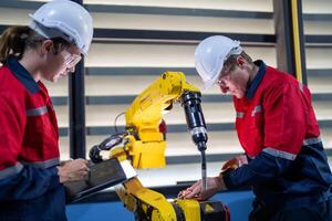 male engineer workers maintenance automatic robotic arm machine in a factory. worker checking and repairing automatic robot hand machine. photo