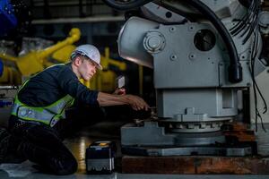 male engineer workers maintenance automatic robotic arm machine in a factory. worker checking and repairing automatic robot hand machine. photo