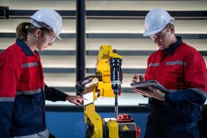 male engineer workers maintenance automatic robotic arm machine in a factory. worker checking and repairing automatic robot hand machine. photo