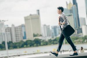Asian businessman walking to work diligently and briskly in the morning in a big city. A man in a business suit, dressed in a smart suit, runs to work during rush hour in corridors and stairs. photo