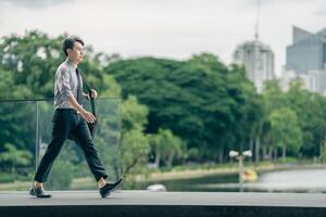 Asian businessman walking to work diligently and briskly in the morning in a big city. A man in a business suit, dressed in a smart suit, runs to work during rush hour in corridors and stairs. photo