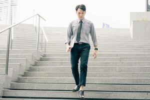 Asian businessman walking to work diligently and briskly in the morning in a big city. A man in a business suit, dressed in a smart suit, runs to work during rush hour in corridors and stairs. photo