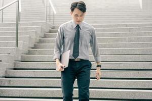 Asian businessman walking to work diligently and briskly in the morning in a big city. A man in a business suit, dressed in a smart suit, runs to work during rush hour in corridors and stairs. photo