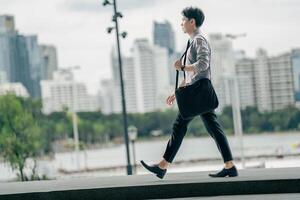 Asian businessman walking to work diligently and briskly in the morning in a big city. A man in a business suit, dressed in a smart suit, runs to work during rush hour in corridors and stairs. photo