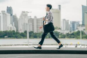 Asian businessman walking to work diligently and briskly in the morning in a big city. A man in a business suit, dressed in a smart suit, runs to work during rush hour in corridors and stairs. photo