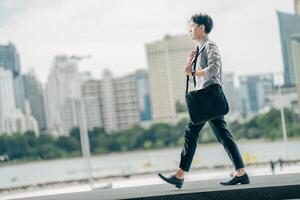 Asian businessman walking to work diligently and briskly in the morning in a big city. A man in a business suit, dressed in a smart suit, runs to work during rush hour in corridors and stairs. photo