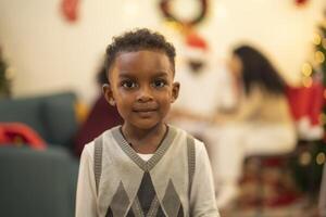 A close up portrait of a young boy smiling during a festive Christmas gathering. The soft bokeh from holiday lights and decorations in the background creates a warm and joyful atmosphere. photo