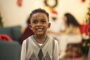 A close up portrait of a young boy smiling during a festive Christmas gathering. The soft bokeh from holiday lights and decorations in the background creates a warm and joyful atmosphere. photo