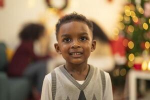 A close up portrait of a young boy smiling during a festive Christmas gathering. The soft bokeh from holiday lights and decorations in the background creates a warm and joyful atmosphere. photo