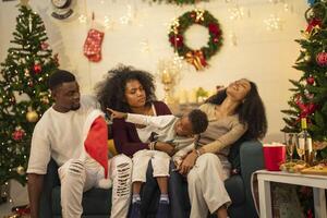 A lively Christmas celebration with three african friends enjoying drinks and holiday cheer on a sofa. The festive atmosphere includes Christmas trees, wreaths, lights, and decorations. photo