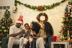 A lively Christmas celebration with three african friends enjoying drinks and holiday cheer on a sofa. The festive atmosphere includes Christmas trees, wreaths, lights, and decorations. photo
