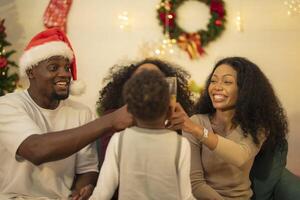 A lively Christmas celebration with three african friends enjoying drinks and holiday cheer on a sofa. The festive atmosphere includes Christmas trees, wreaths, lights, and decorations. photo
