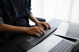 Asian man software engineer Working on Computer at office desk for writing program code IT Software Engineer finding errors tech support devops creating digital photo