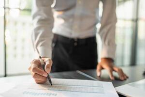 Close up of businessman hands signing or writing document paperwork and report Auditor analysis male professional hand making notes with Business Document. photo