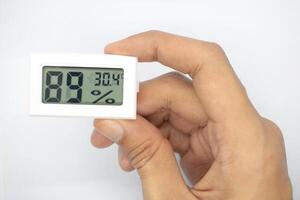 holding a humidity measuring thermometer, small size, portable, on a white background. photo