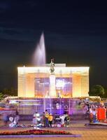 Bishkek, Kyrgyzstan - 25th september, 2023- tourist visit Manas Statue in Ala-Too Square. State history museum and fountain with tourist in city square. Sunset blue hour sky background photo