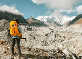 Woman trekker alone stands treks to Gokyo Ri in Sagarmatha national park with mountains background. EBC trekking. Everest base camp trekking in fall, autumn sunny dry weather photo