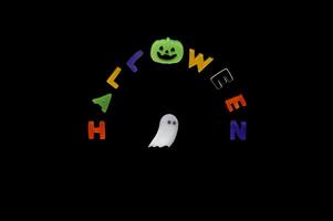 Halloween background with white ghost sheet and alphabets gel sticker on black background. Minimal concept. photo