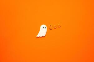 Halloween background with gel stickers of white ghost sheet and alphabets on orange background. Minimal concept. photo