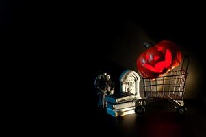 Halloween background with Jack o lantern that have light inside on shopping cart with small decorations on black background. Minimal concept. photo
