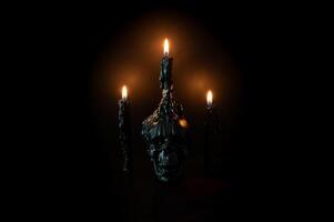 Halloween background with skull that have light candle on it with another candles on black background. Minimal concept. photo