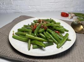 Stir-fried green beans with garlic and chili on white plate. Asian style food. photo