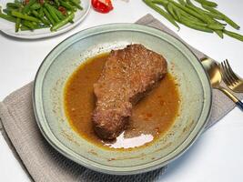 Beef stewed with herbs and spices in a plate on the table. Slow cooked beef. photo