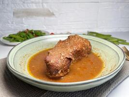 Delicious beef stewed with herbs and spices in a plate on the table with stir fry green beans. Slow cooked beef. photo