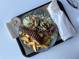 Kebab with French fries and salad on a plate in a restaurant photo