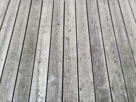 A rustic and aged wooden surface with vertical planks, featuring a light gray color, visible grain patterns, and slight variations in texture perfect for creative projects or background photo