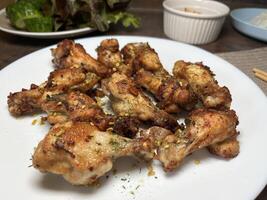 Close up Fried chicken thighs sprinkled with onions and parsley on a white plate photo