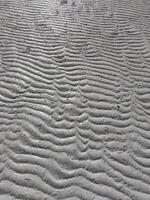 Sea sand has a unique texture due to the waves of sea water on the beach photo