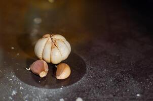 Garlic on the black table with flour food powder and circle round traces photo